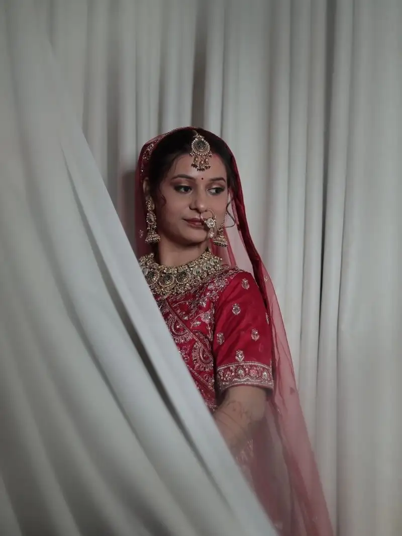 Bride in red framed by a sheer white drape, with classic red-lip bridal makeup