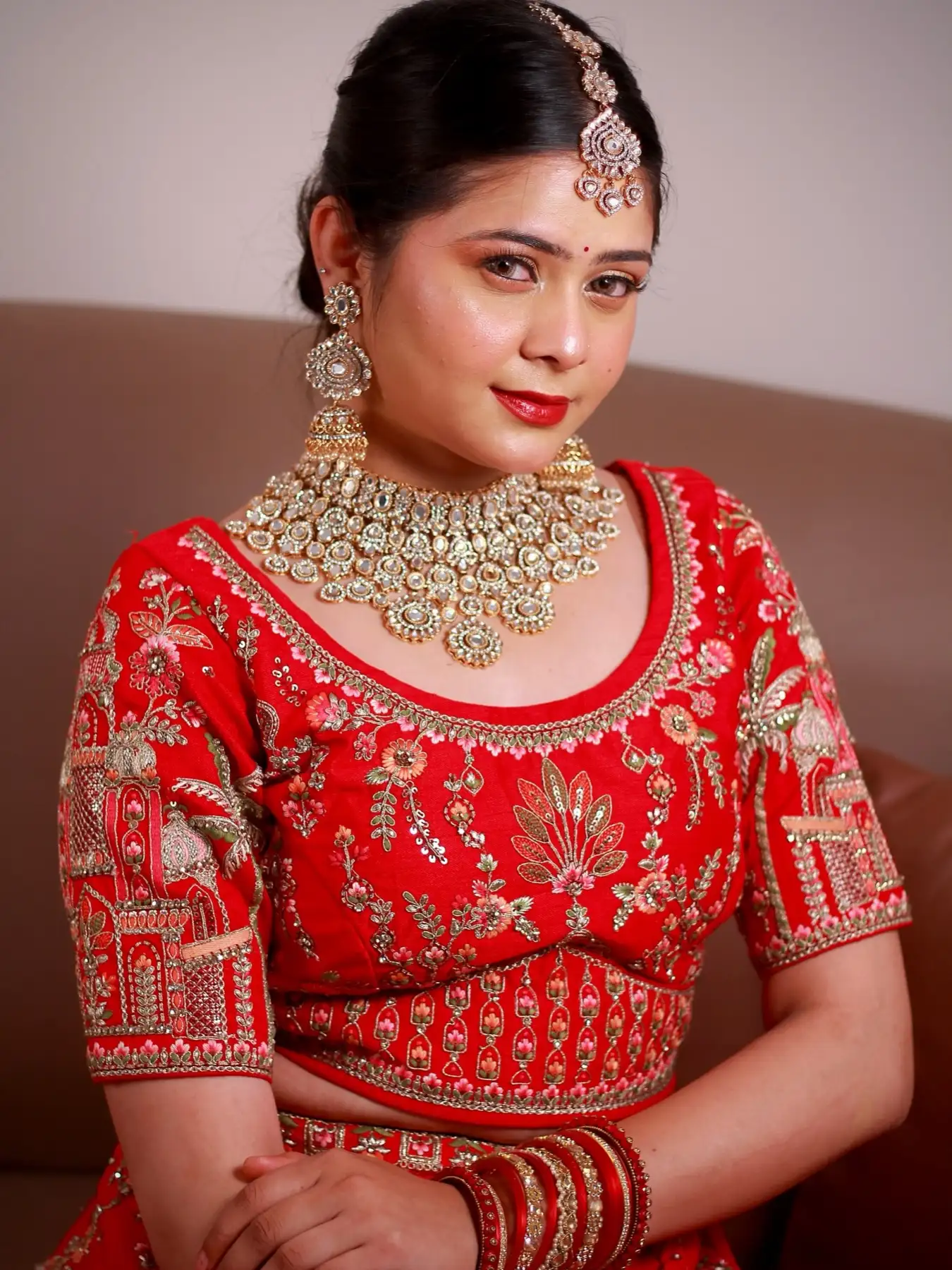 Close-up of a bride in a red embroidered lehenga with kundan jewellery and a bold red lip